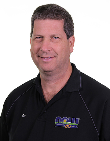 portrait of Dan Richard  - light-skinned, dark-haired male wearing a black polo shirt with NOW logo against a white background