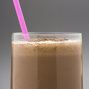 A drinking glass with a bright pink straw is filled with a brown Cinnamon Chocolate Protein Shake.