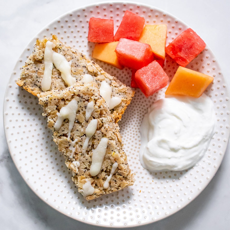 Lemon Poppyseed Oat Bars on a white plate with melons 