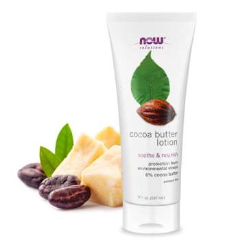 Bottle of NOW Solutions Cocoa Butter Lotion with a chunk of raw cocoa butter and cocoa nibs and leaves behind