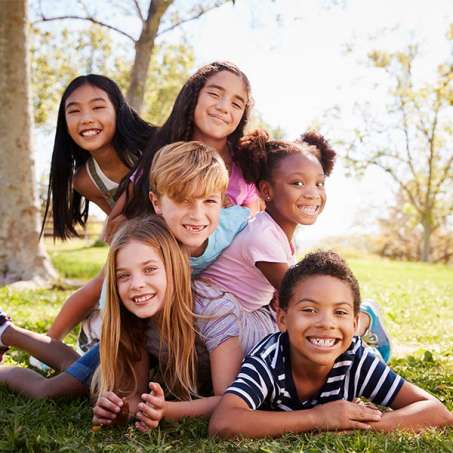 group of multiracial, multi-gendered children smiling at camera