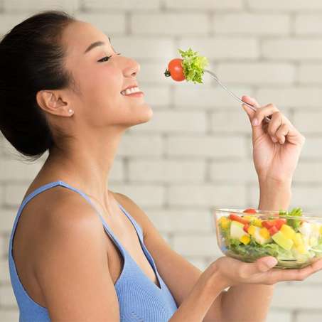 light-skinned, female presenting person enjoying eating a salad