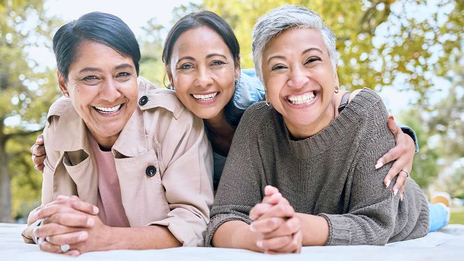 three older females lying on their stomachs smiling at the camera