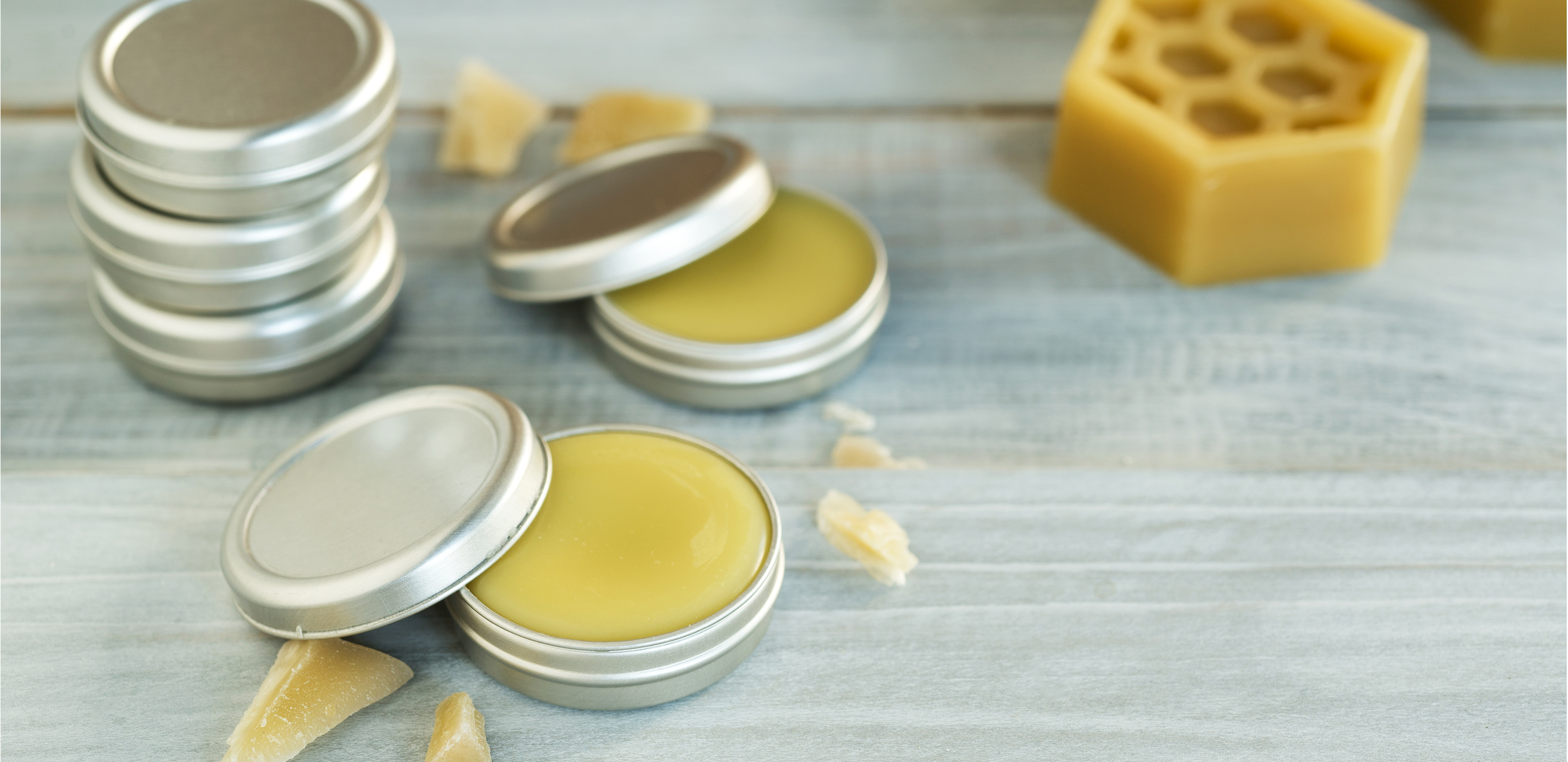 metal jars with lip balm inside. Beeswax chunks on the table