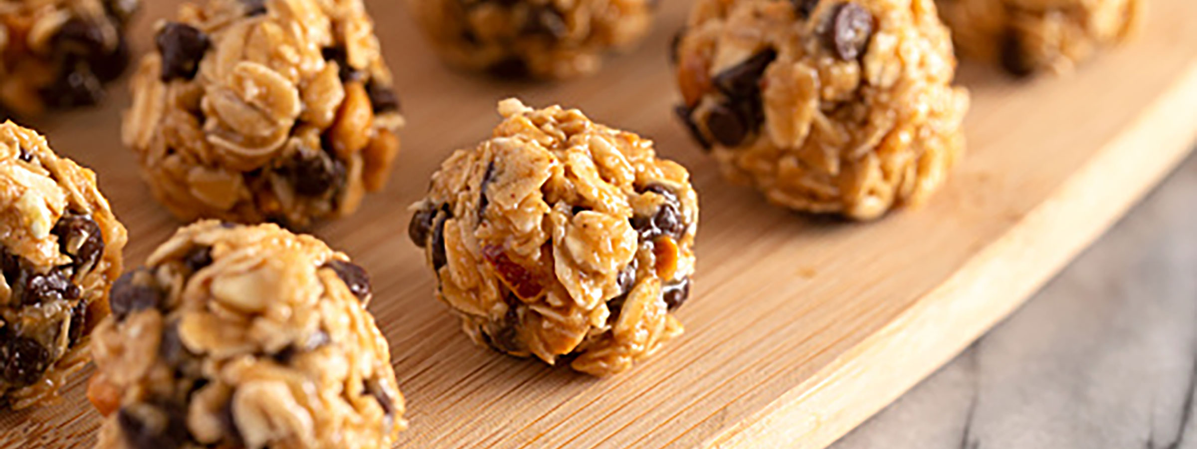 wooden tray with rows of bite-size protein balls with chocolate chips