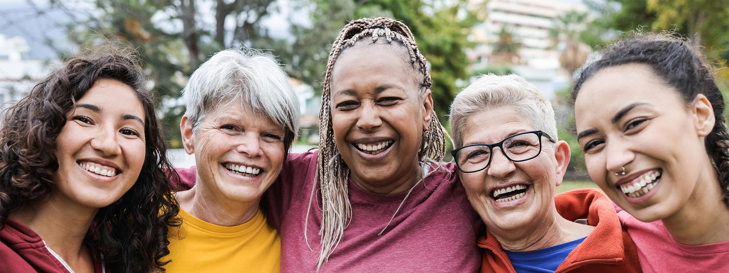 five women ranging in age and skin color smiling at the camera