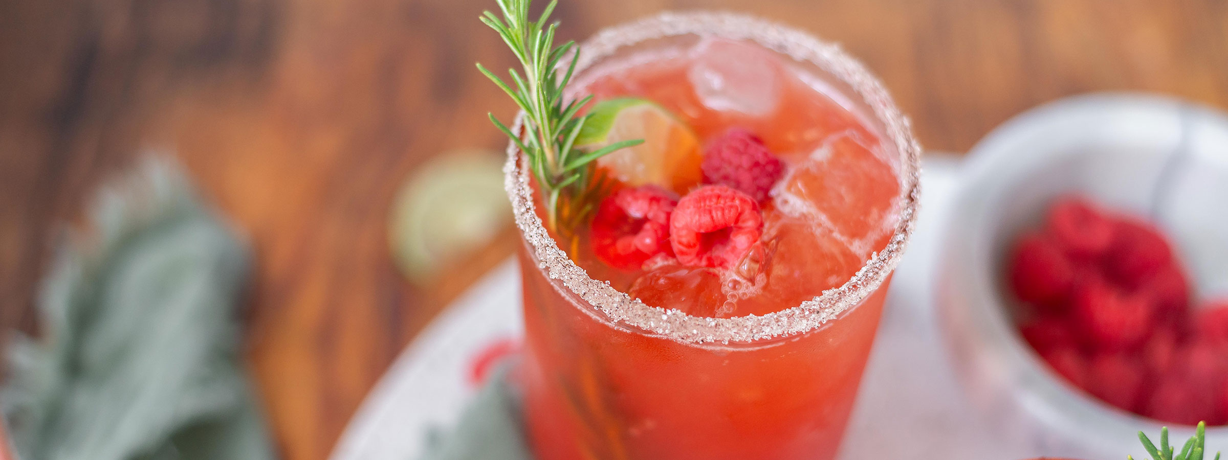 clear glass filled with red iced tea with sugar around the rim and a green sprig rising from the top