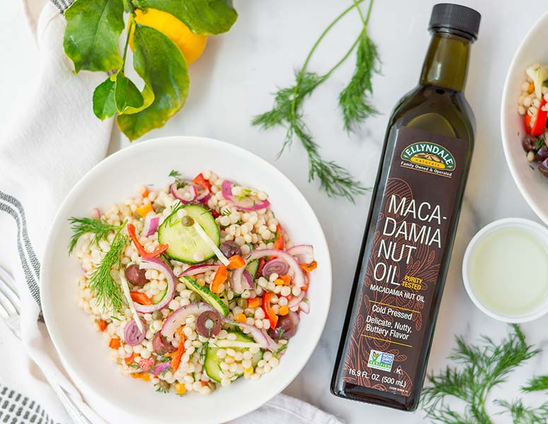 bowl of mediterranean salad next to a bottle of ellyndale macadamia nut oil