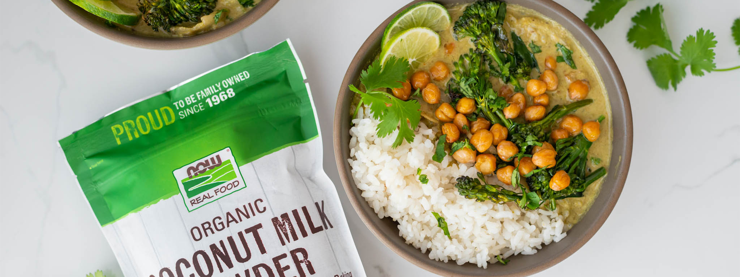 top view of bowl of coconut lime curry next to a bag of NOW powdered coconut milk