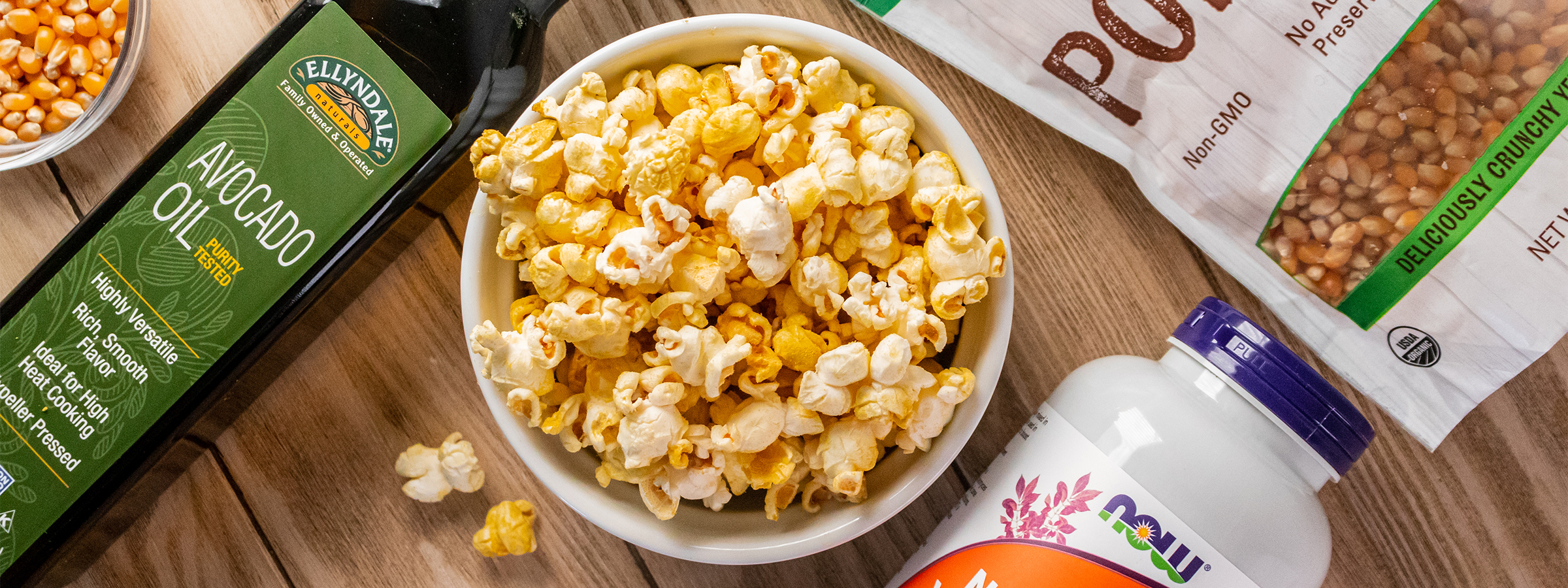 top view of Cheesy Vegan Popcorn with NOW Popcorn kernals and NOW nutritional yeast and Ellyndale Avocado Oil