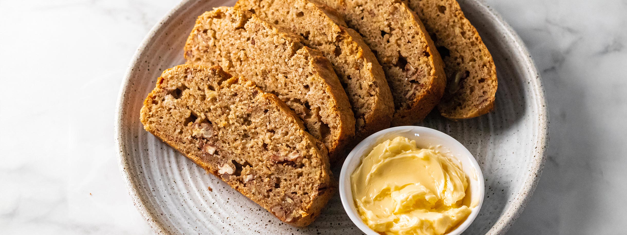 white plate with slices of Rice Bran Banana Nut Bread and little 