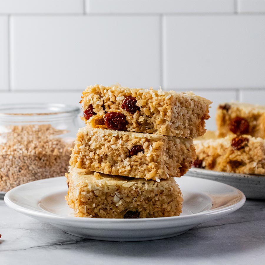 3 steel cut oat golden and coconut bar square stacked on white plate