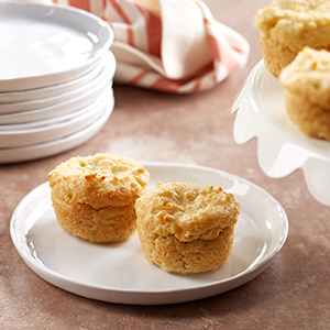 A white ceramic plate on a table holds two Organic Vanilla Millet Muffins