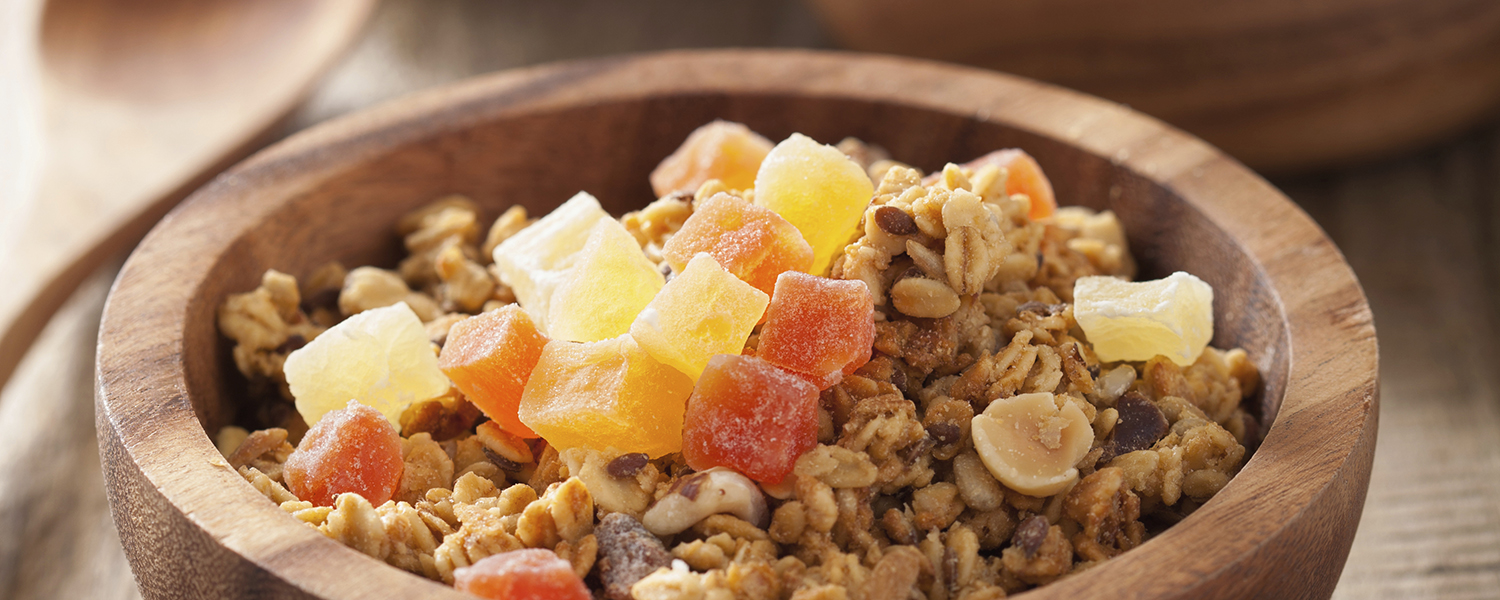 A small wooden bowl on a wooden table is filled with Bahama Mama Healthy Tropical Oatmeal