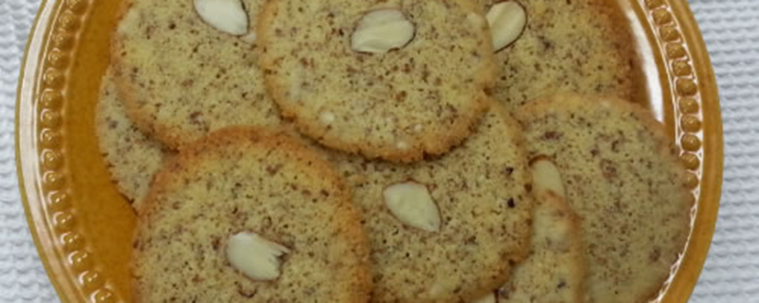 A tan plate with Crisp Frangipane Cookies. A single almond slice is the middle of each cookie.