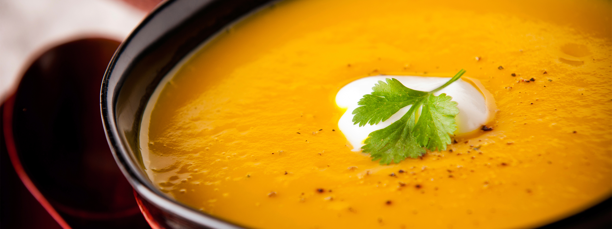 A closeup of Curried Cauliflower Soup in a black soup bowl