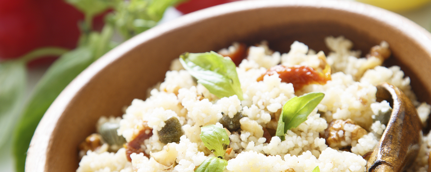 A small wooden bowl holding a dish of Mediterranean Couscous with Toasted Walnuts