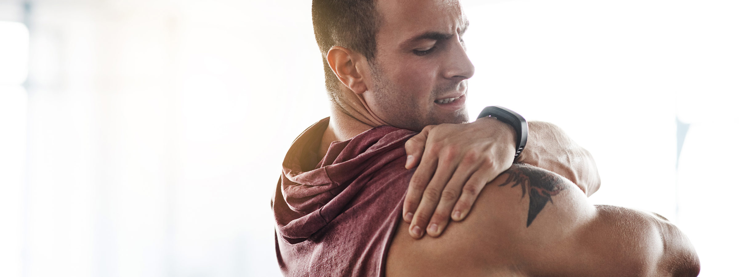 light-skinned, male presenting person rubbing oil on shoulder