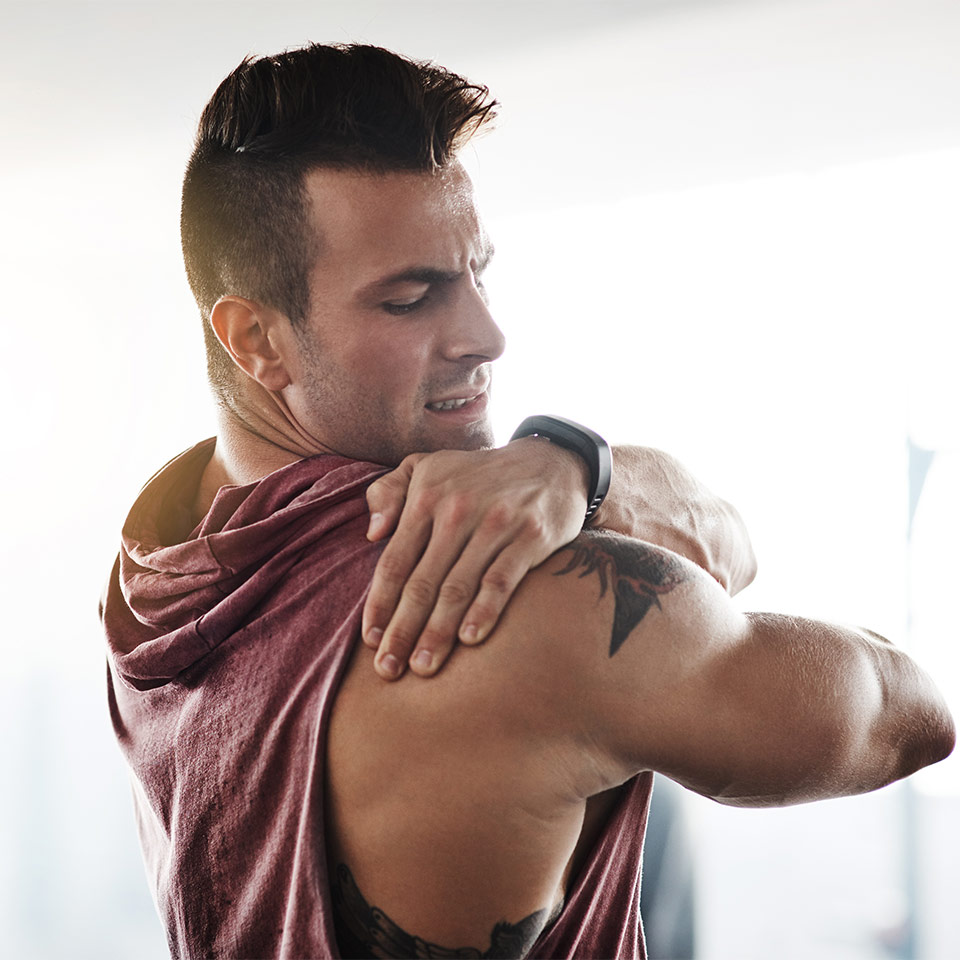 light-skinned, male presenting person rubbing oil on shoulder