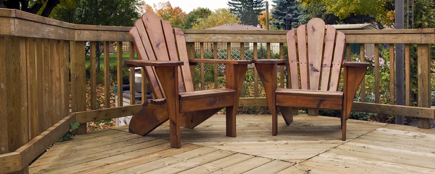 A suburban backyard wooden porch, prominently featuring two wooden deck chairs.