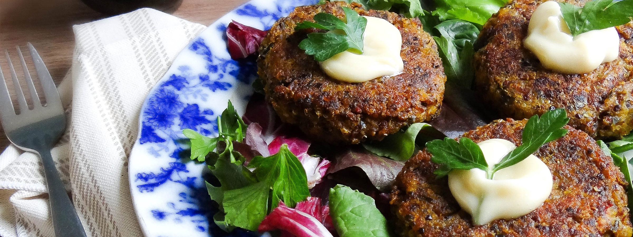 A white plate with blue floral decorations holds several Winter Squash & Quinoa Rissoles. 
