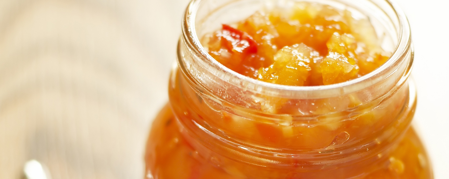 A mason jar on a wooden table holds several servings of Super Fruit Chutney.