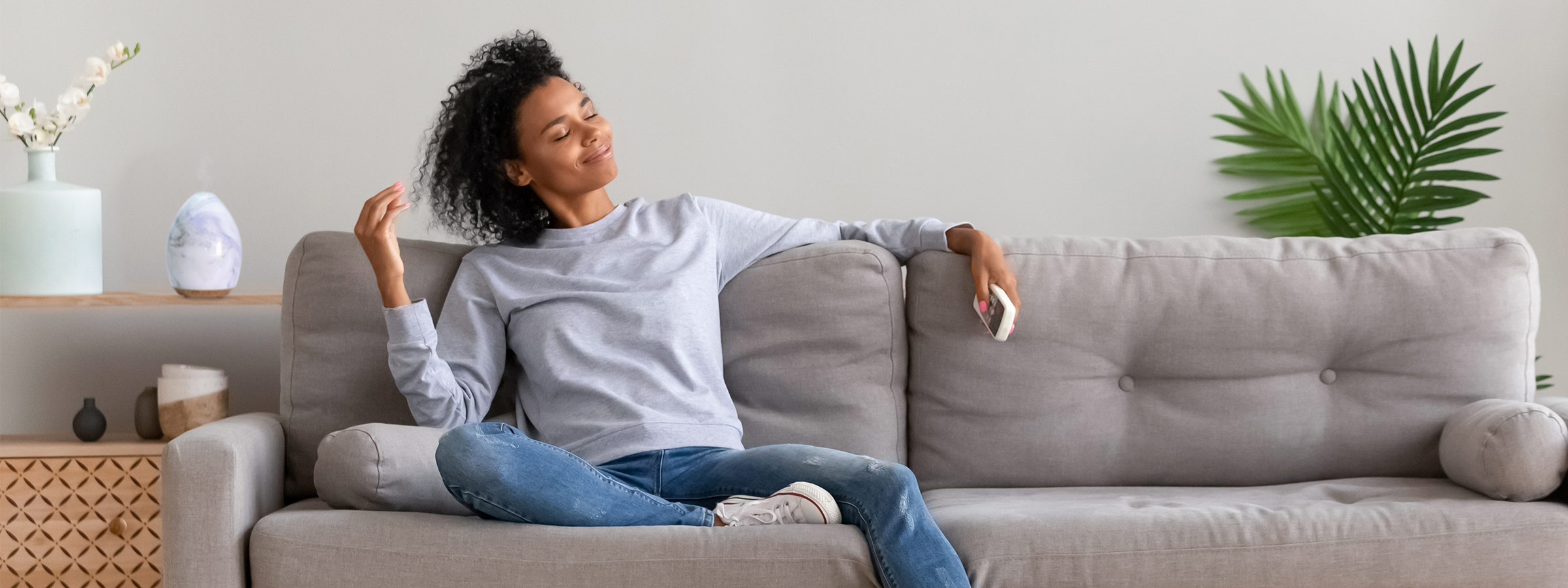 dark-skinned, female-presenting person on a couch, smelling the air