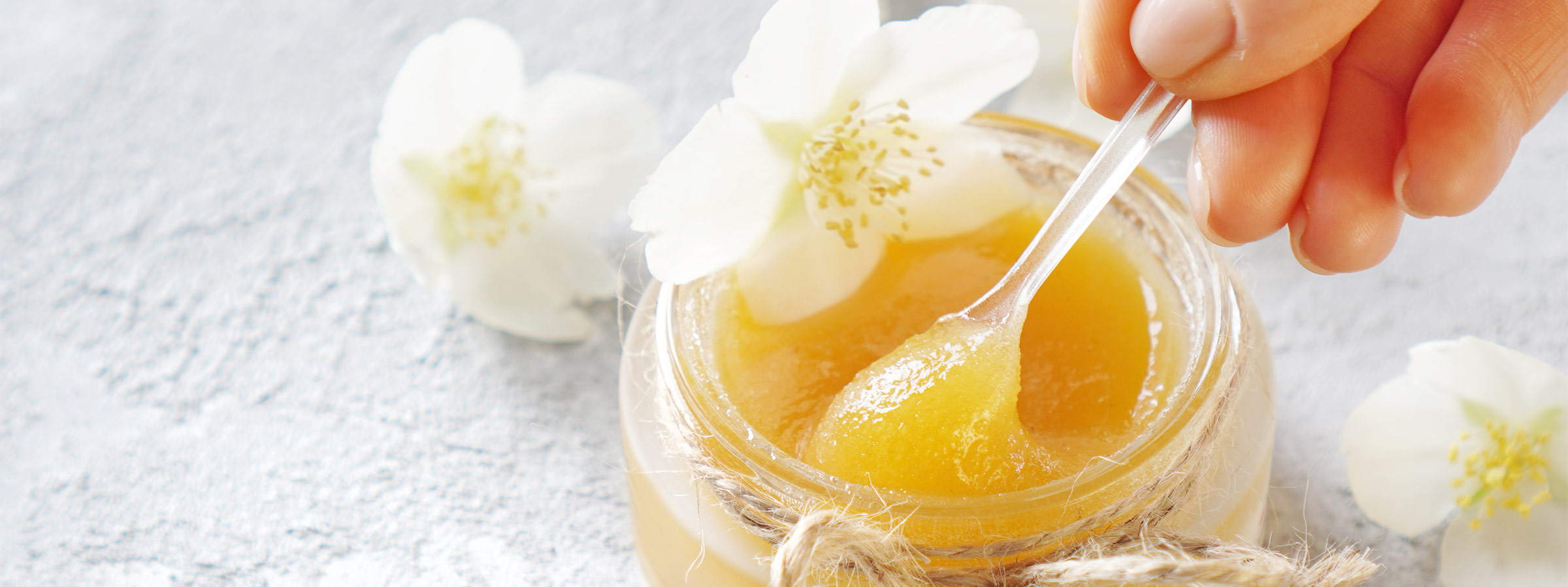 small jar of honey mix being spooned out with a tiny spoon 