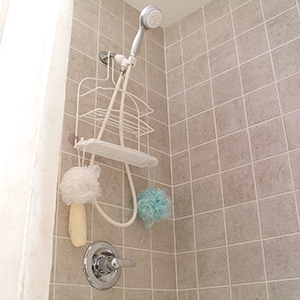 The inside of a shower with brown wall tile