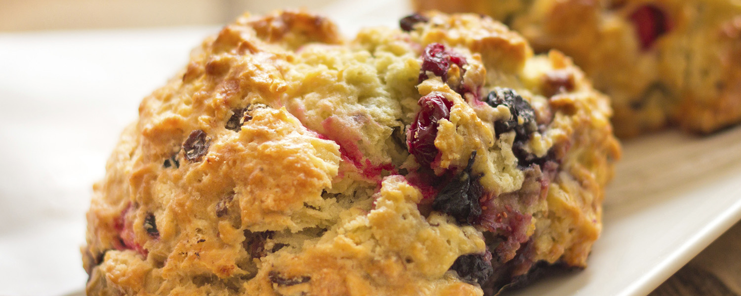 A closeup of a Triple Berry Scone on a white ceramic platter. 