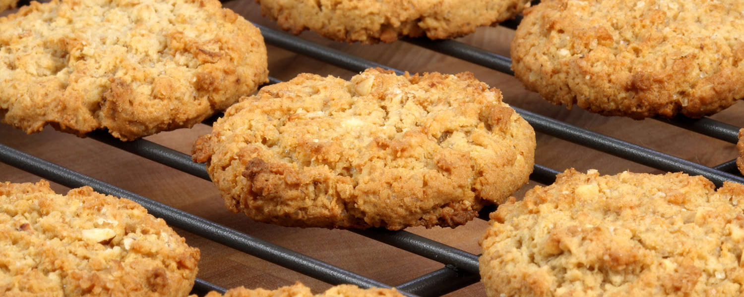 Several Vegan Tropical Oatmeal Cookies on a black wire baking rack on a wooden table.