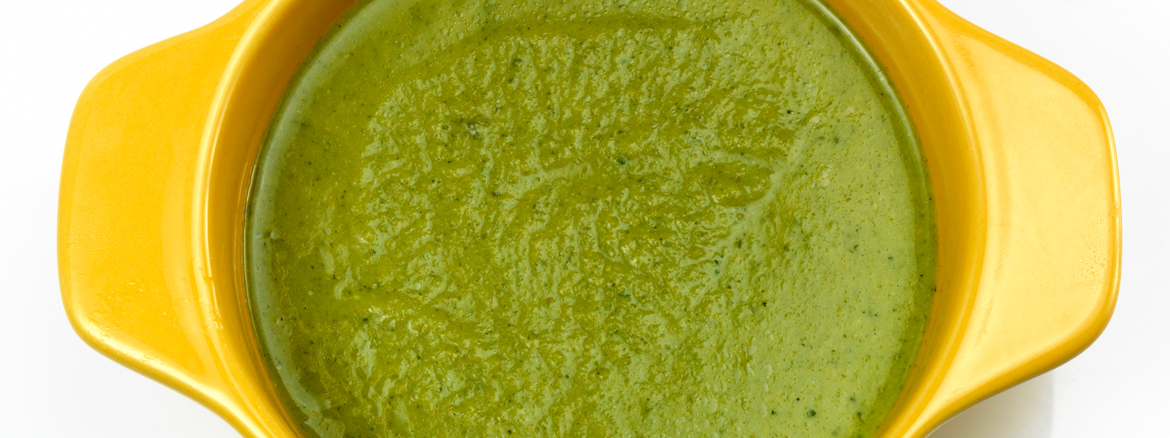 A yellow bowl on a white table holding servings of dark-green Vegan Coconut Matcha Panna Cotta.