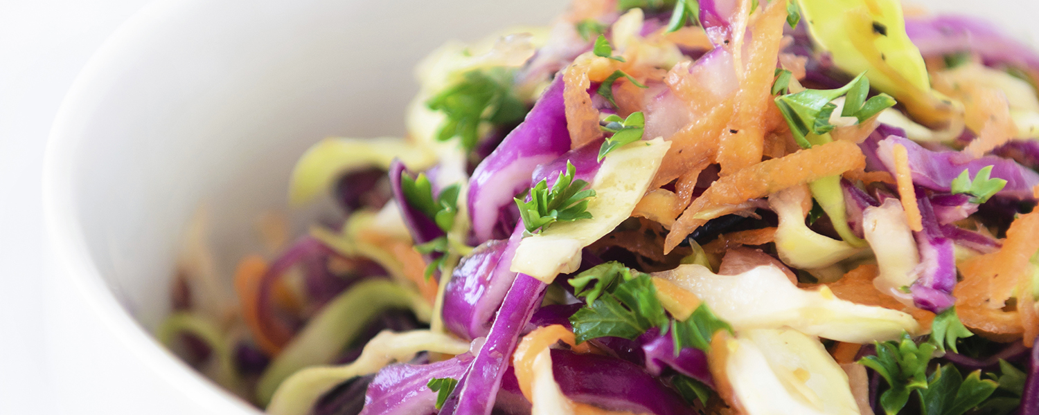 A closeup of a serving of Zesty Lime Slaw in a white ceramic bowl.