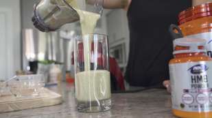 smoothie being poured into a glass NOW Sports HMB Powder next to glass