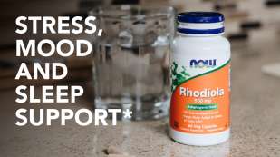 Stress, Mood & Sleep Support with NOW Rhodiola white plastic bottle on a counter next to a glass of water.