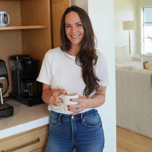 Kelly LeVeque Standing in her kitchen holding coffee cup