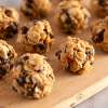 three rows of bite-size protein balls with chocolate chips on a wooden tray