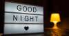 A sign with the inscription good night with turned on table lamp on the background