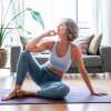 light skin female presenting senior woman sitting on a yoga mat looking away and smiling