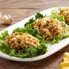 A white ceramic platter on a wooden table holds several servings of Organic Chicken Curry Salad