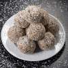 A white ceramic plate on a black countertop is stacked with Chocolate Macaroons