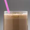 A drinking glass with a bright pink straw is filled with a brown Cinnamon Chocolate Protein Shake.