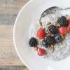 A white ceramic dish on a wooden table holds a serving of Chia Flax Hot Pudding (FO' MEAL)