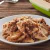 A white ceramic plate on a wooden table holds a serving of Gluten Free Apple Crisp.