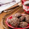 A decorative red and white plate on a wooden table holding Gluten Free Cacao Cookies.