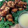 A closeup of several Harissa Chicken Wings. A small dipping bowl is also part of the platter.