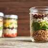 Several mason jars hold servings of Roasted Pecan & Pumpkin Seed Mason Jar Salad