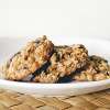 A white ceramic bowl on a wicker placemat holds Ultimate Organic Oatmeal and Goldenberry Cookies