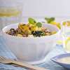 A white ceramic bowl on a blue and white placemat holds a serving of Winter Harvest Quinoa Salad