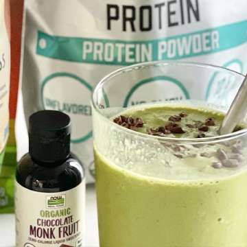 light green matcha chip smoothie in a glass surrounded by ingredients